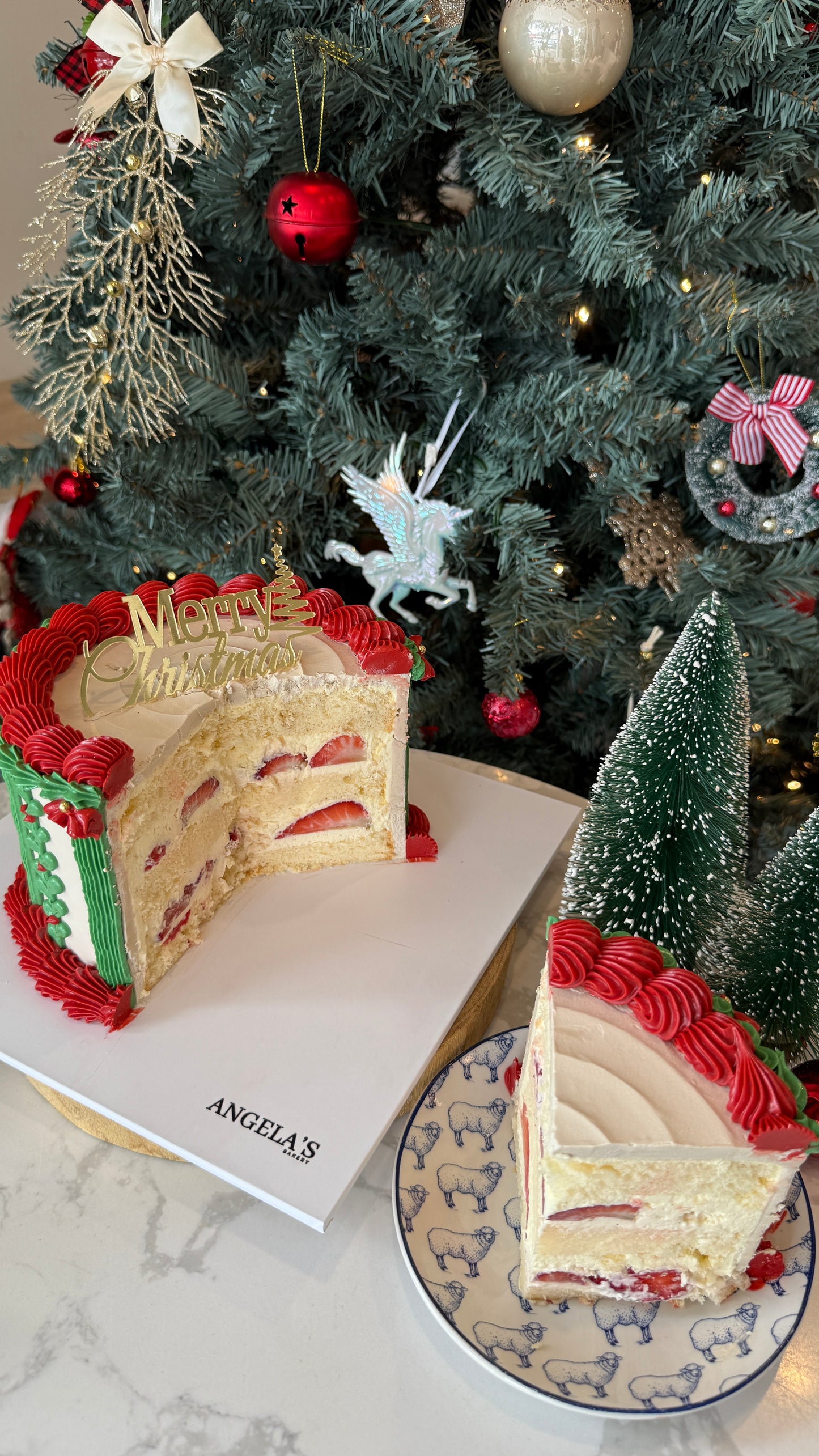 Slice of Christmas-themed cake on a plate with a decorated tree in the background