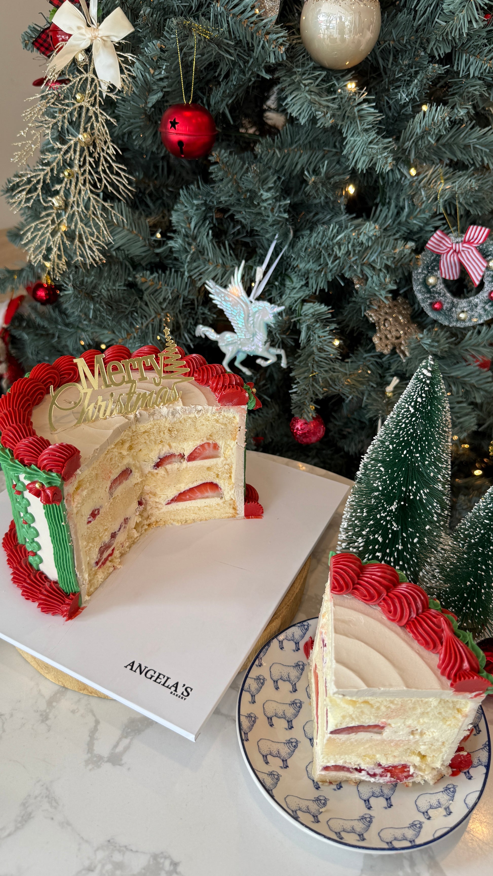 Slice of Christmas-themed cake on a plate with a decorated tree in the background